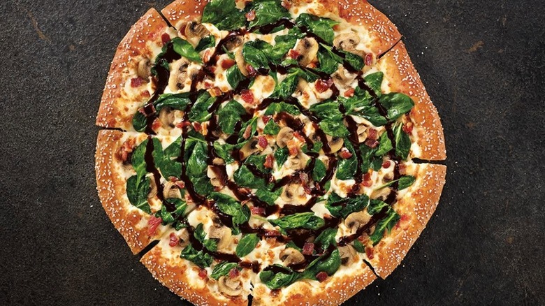 Close up of pizza with greens and balsamic drizzle on slate