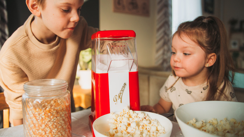 Brother and sister waiting for popcorn to come out of popcorn maker