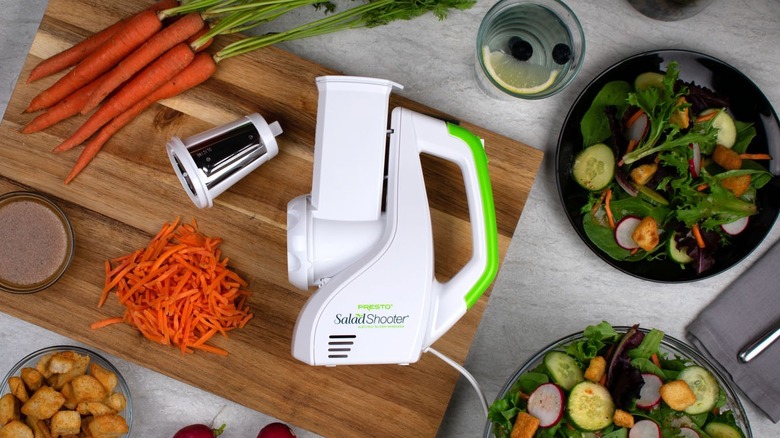 Salad shooter appliance surrounded by salad veggies