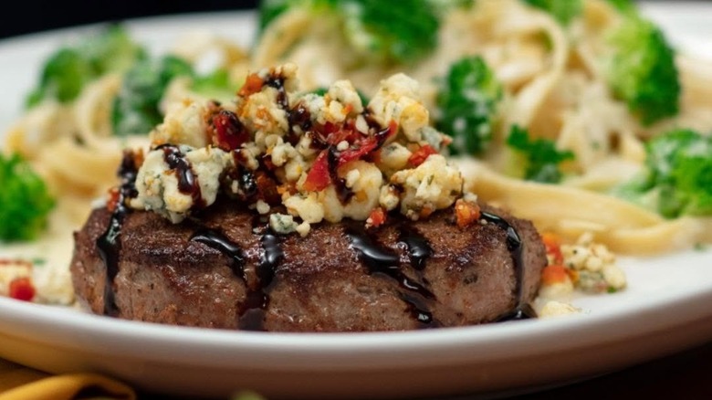 Close up of steak topped with cheese on white plate