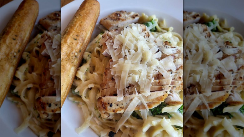 Broccoli Chicken Alfredo with breadstick on white plate, mirrored image