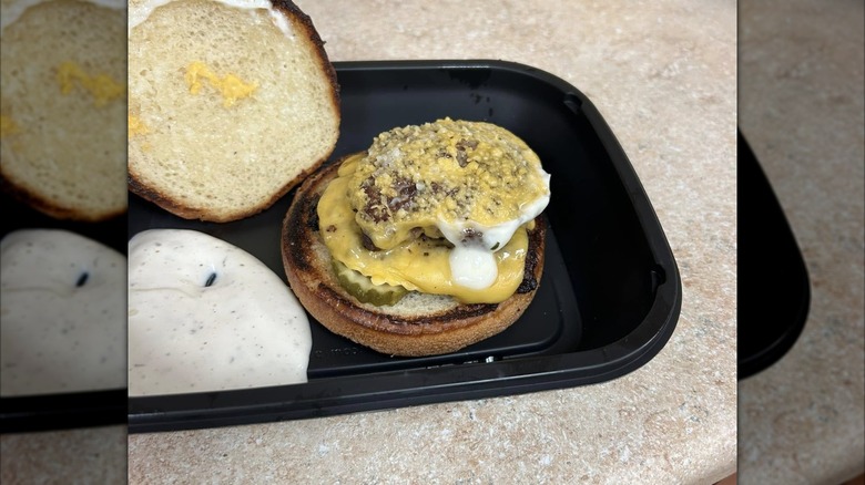 small cheeseburger in takeout dish, mirrored image