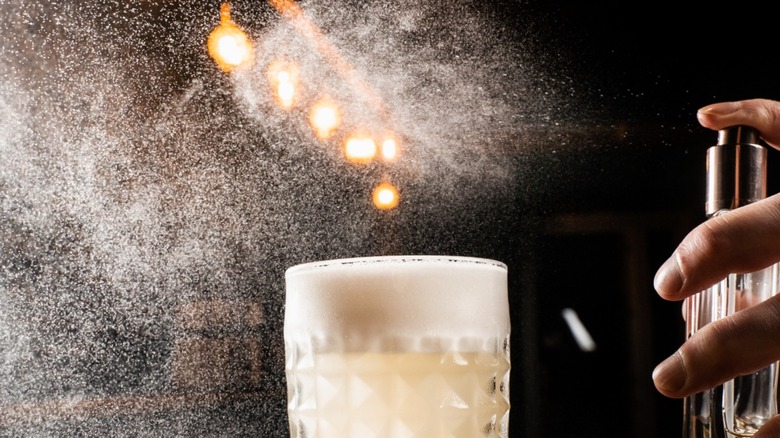 Bartender is spraying atomized spirit over a cocktail.