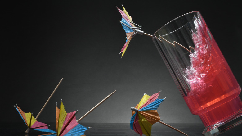 A sloshing red cocktail with cocktail umbrellas