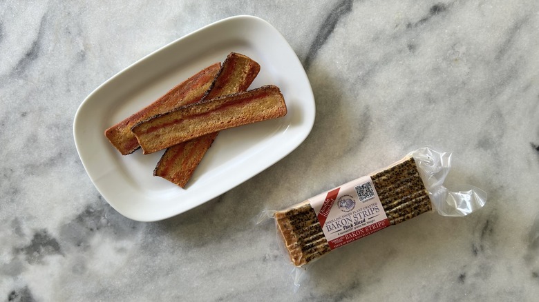 Vegan bacon strips next to a Thrilling Foods package