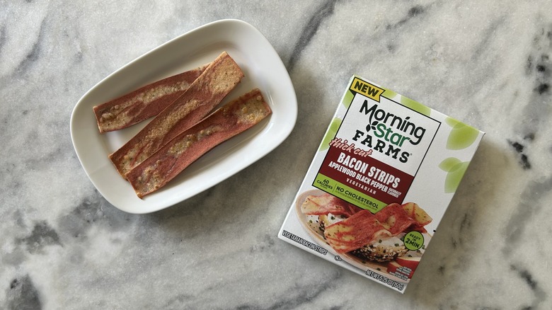 Thick-cut, plant-based bacon strips next to a MorningStar Farms box