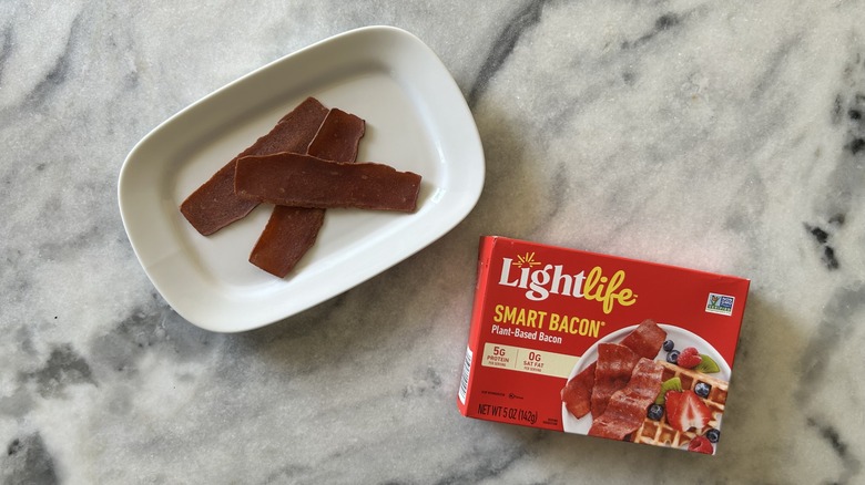 Strips of vegan bacon next to a LightLife Smart Bacon package