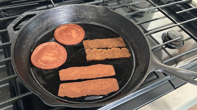 Various types of plant-based bacon in a cast iron skillet