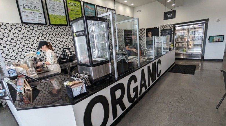 Employees preparing smoothie orders behind Clean Juice counter branded with the word "organic"