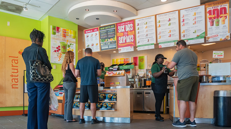Folks standing in line for smoothies at colorful Jamba shop