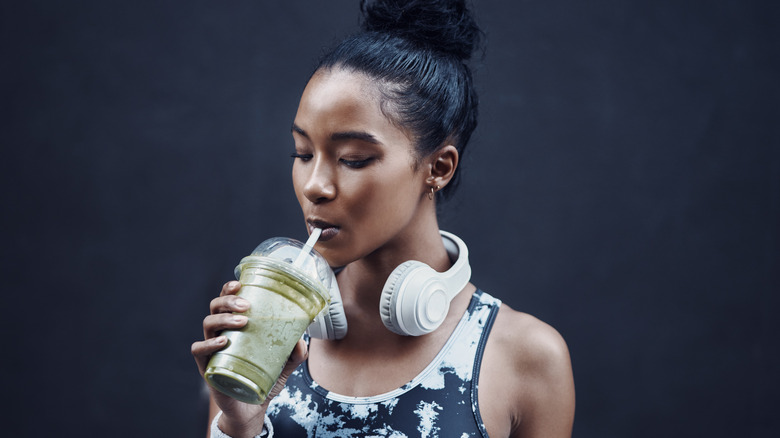 Woman in athletic attire sipping on smoothie
