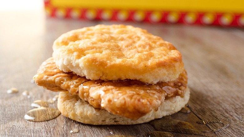close up of bojangles cajun chicken biscuit with honey dripping on wooden table