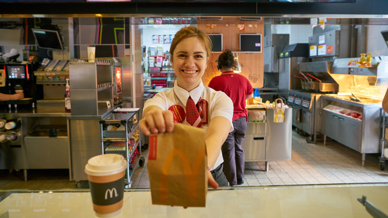 worker holding up customers order in bag at McDonald's