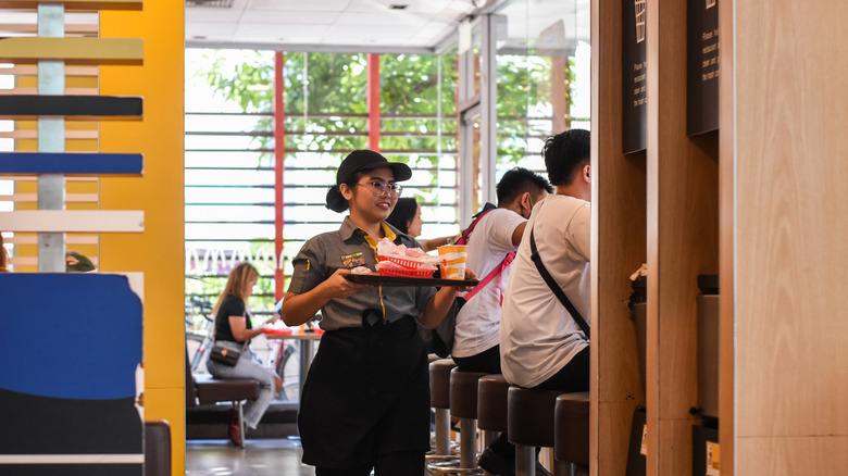 McDonald's worker carrying tray of food through restaurant