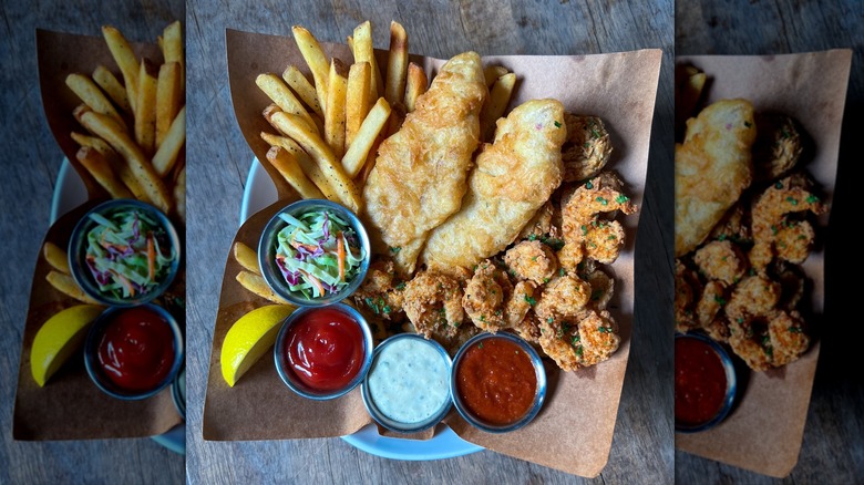 Fries, fried fish, and fried shrimp with sauces in white bowl