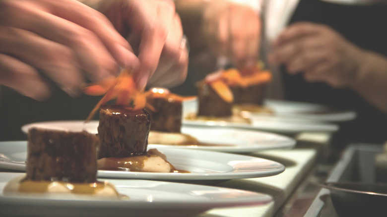 Chefs cooking at a fine dining restaurant plating food in real life, close-up.