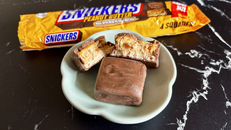 Snickers peanut butter candy bar squares with wrapper in background