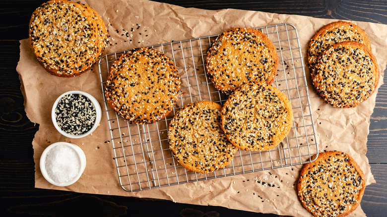 Sesame cookies on parchment paper against a dark, wooden background