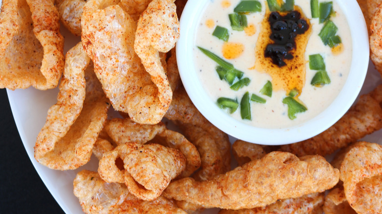 A plate of deep-fried pork rinds with sauce, viewed from above
