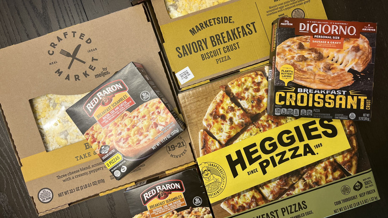 7 different store-bought breakfast pizzas in boxes.