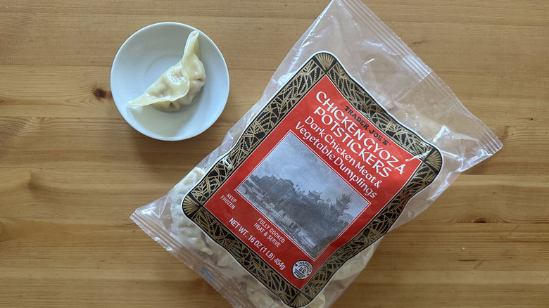 Trader Joe's Chicken Gyoza Potstickers packet and a dumpling on wooden table