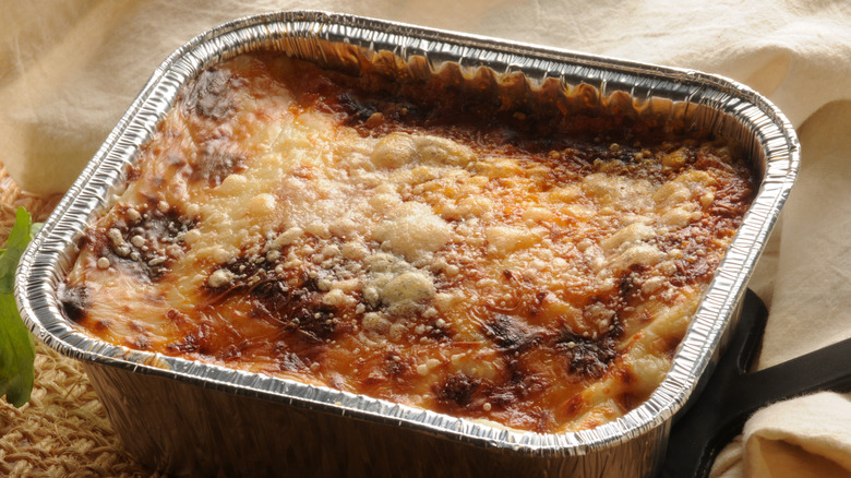 Frozen lasagna in baking tray, topped with cheese