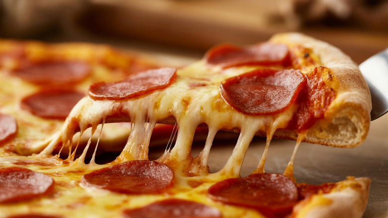 Lifting slice of pepperoni pizza with cheese pull