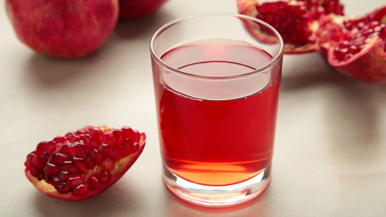 glass of pomegranate juice and wedge of fresh pomegranate