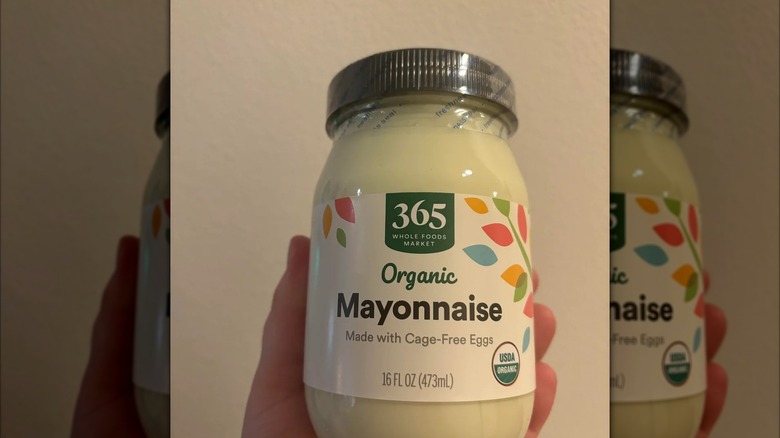 Someone holding an unopened jar of 365 Organic Mayonnaise.