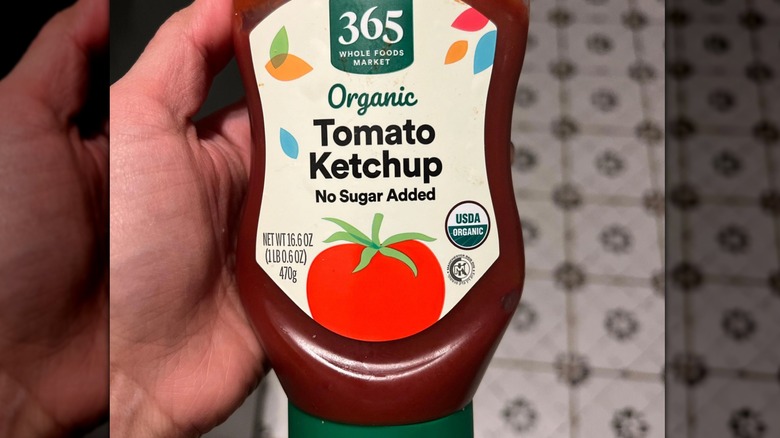 Someone holding a bottle of 365 Organic Tomato Ketchup
