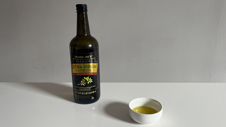 A bottle of Trader Joe's olive oil with a bit poured into a little white dish beside it