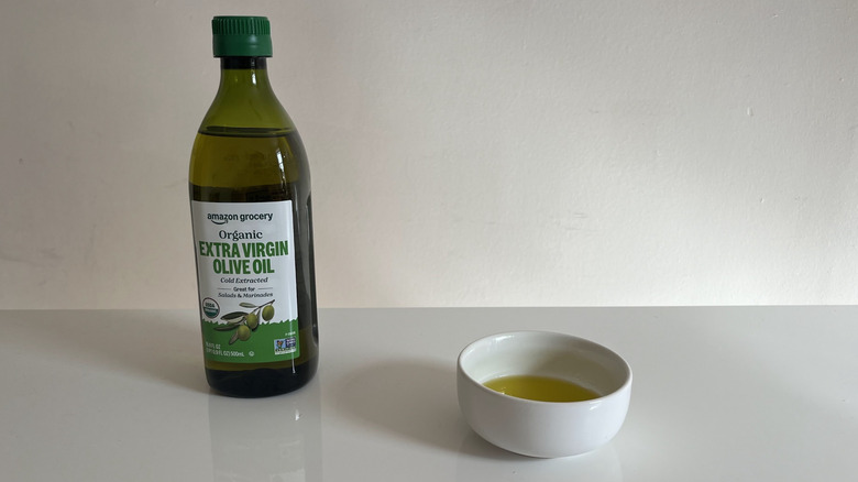 A bottle of Amazon olive oil beside a small white dish containing oil