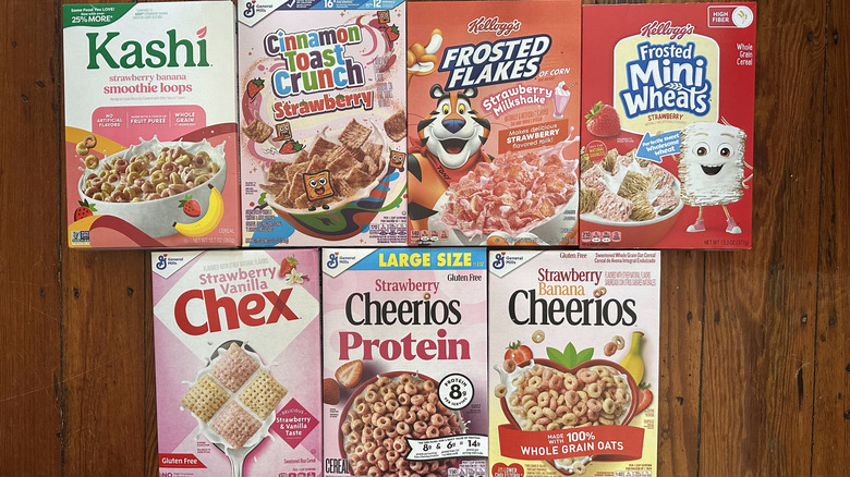 Variety of strawberry cereal boxes on wooden surface