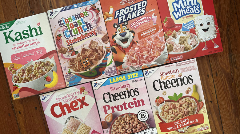 Variety of strawberry cereal boxes on wooden surface