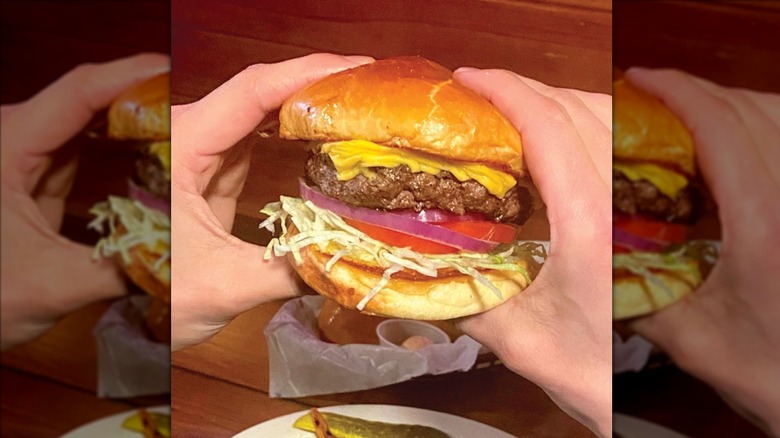 Hands holding Texas Roadhouse all-American cheeseburger