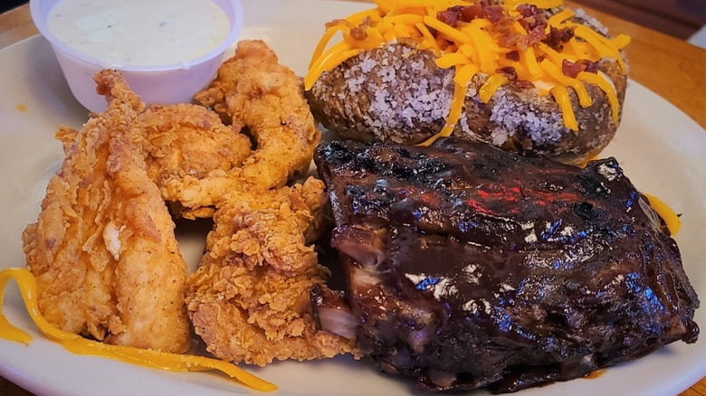 Texas Roadhouse chicken critters and ribs with baked potato on white plate