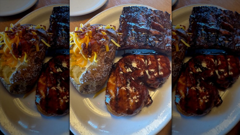Grilled BBQ chicken and ribs with baked potato on white plate