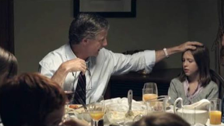 Man putting his hand on little girl's head at dinner table