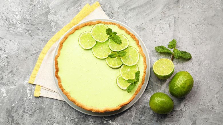 Top-down shot of key lime pie topped with lime slices and mint leaves