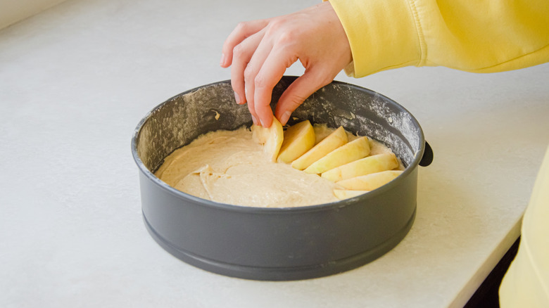 Woman arranging fruit slices in dark metal pan