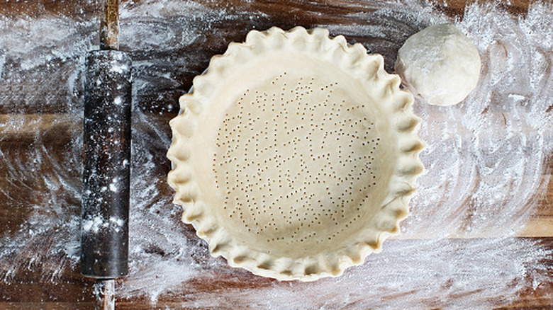 Top-down shot of pie crust on floured wooden surface