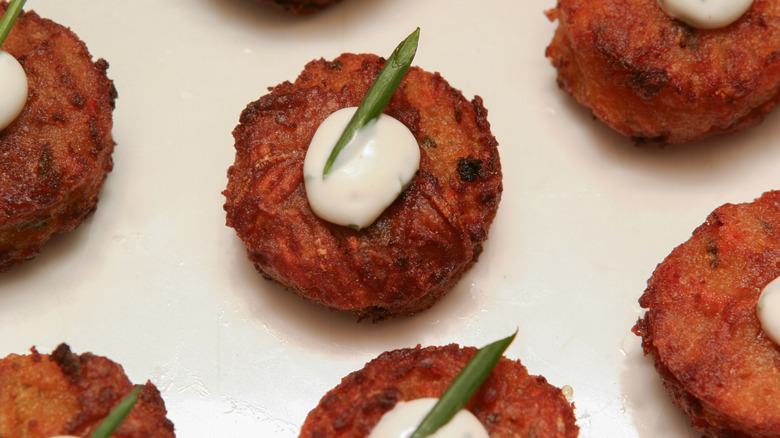 golden cakes topped with white sauce and spring onion