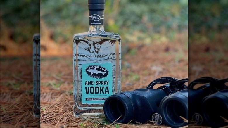 Label view of Dogfish Head Awe-Spray Vodka outside alongside binoculars on the ground