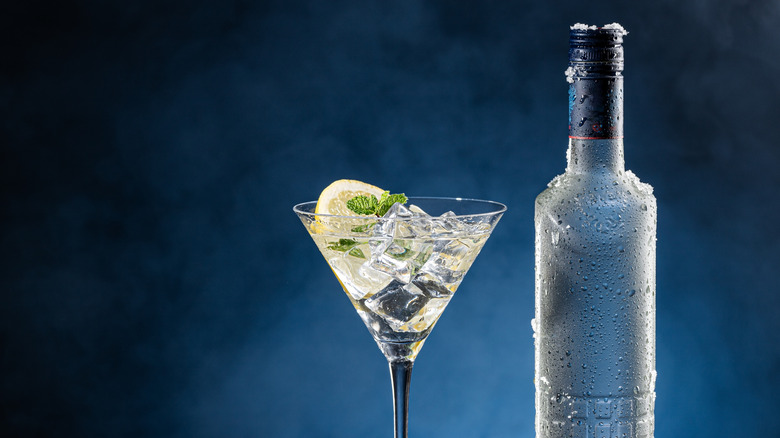Vodka Cocktail glass and ice-cold bottle against a blue ombre background