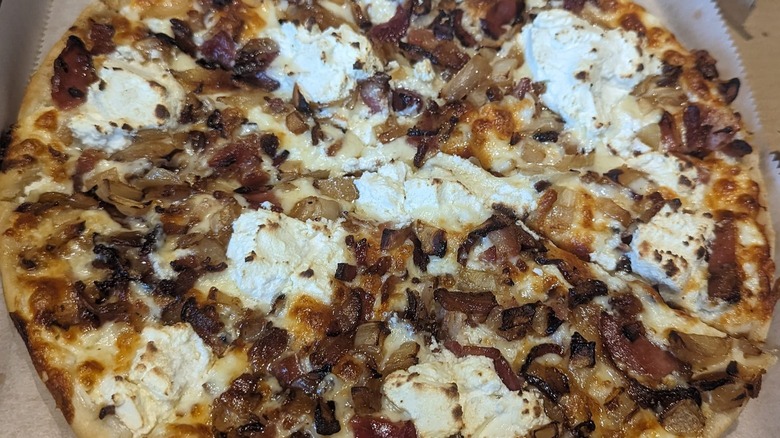 Pizza topped with bacon, crème fraîche, caramelized onions, and ricotta