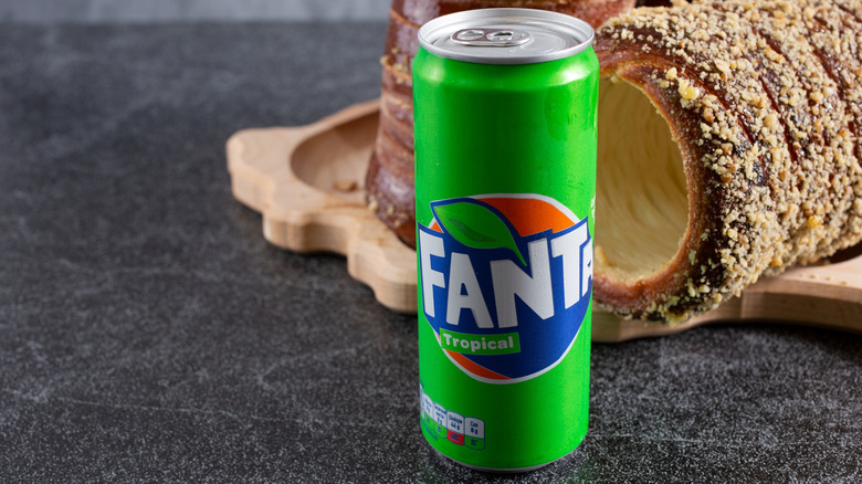 Green can of Fanta Tropical on dark surface