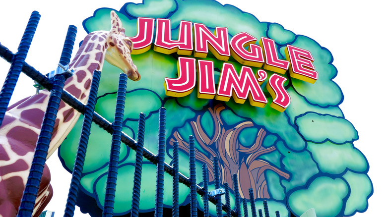 A big tree sign with Jungle Jim's on it and giraffe figure next to it