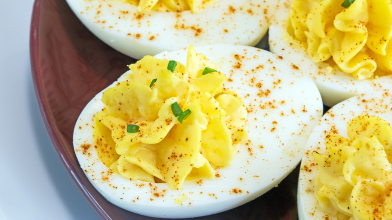 Close-up of deviled eggs on a dark red plate