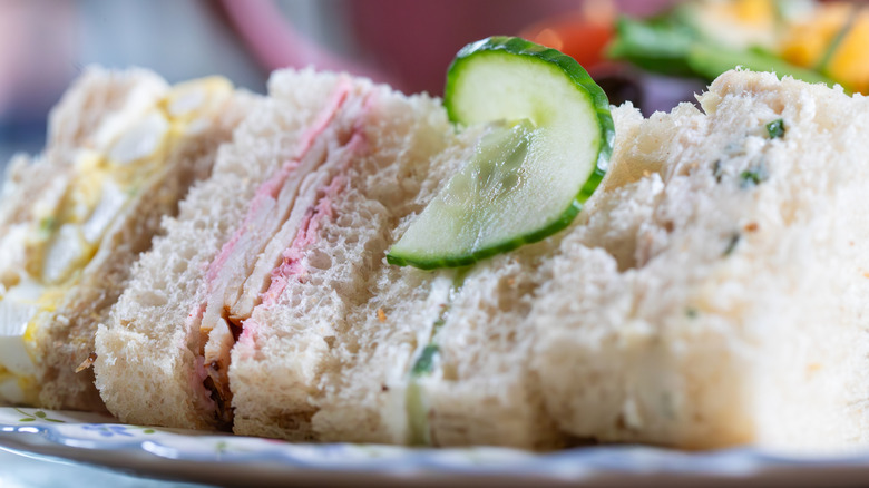 Row of mini finger sandwiches topped with a cucumber slice