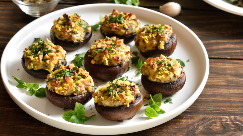 Stuffed mushrooms on a white plate on wooden table